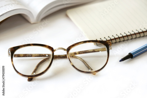 notebook with glasses and pen on table, close up
