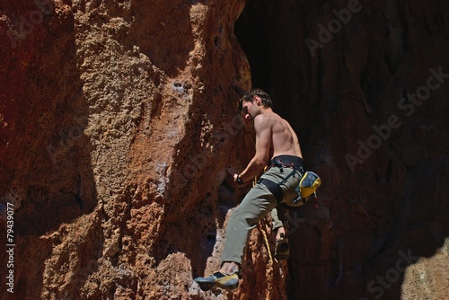 Powerful male climber climbing rock face