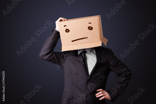 Businessman gesturing with a cardboard box on his head with stra
