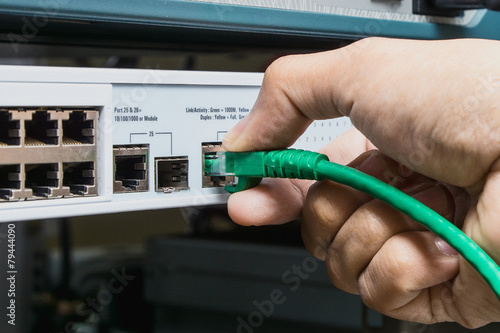 Obraz na płótnie man connecting network cable to switch