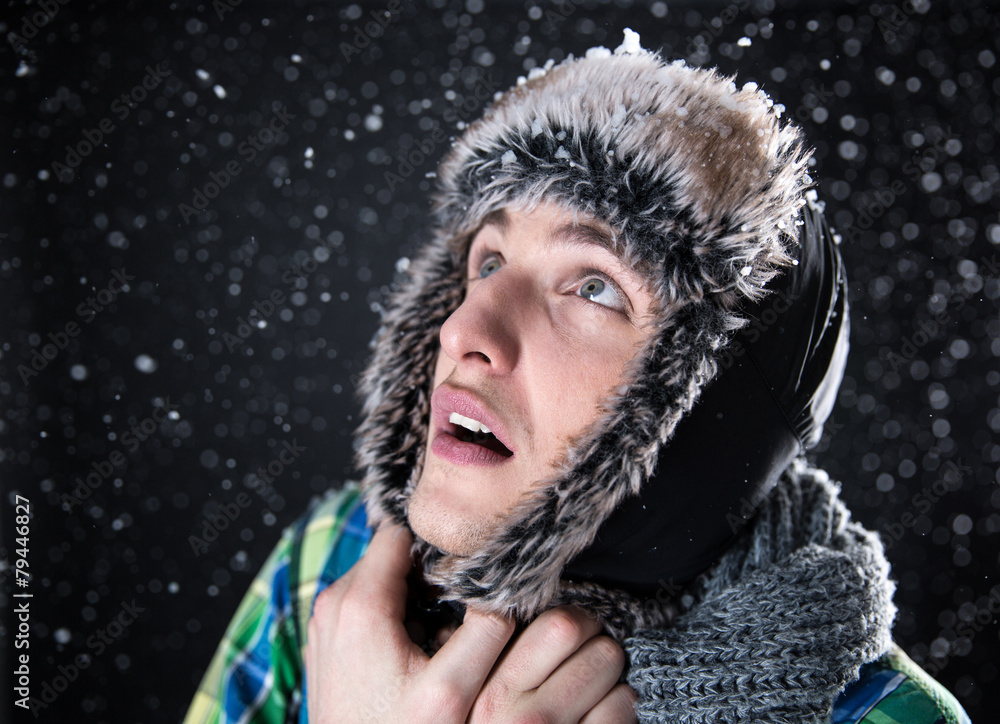 Surprised young man looking up with snow on background Surprised young man looking up with snow on background
