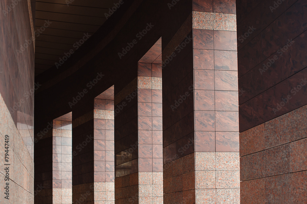 Fototapeta premium Row of columns with sunlight in the gaps and reflected in shiny