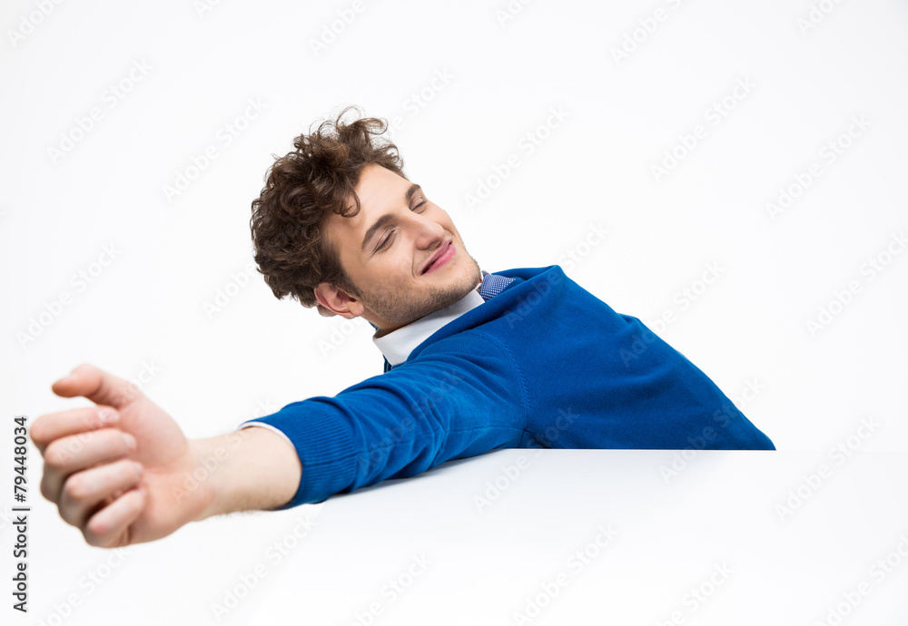 Happy young businessman sitting at the table and stretching Happy young businessman sitting at the table and stretching
