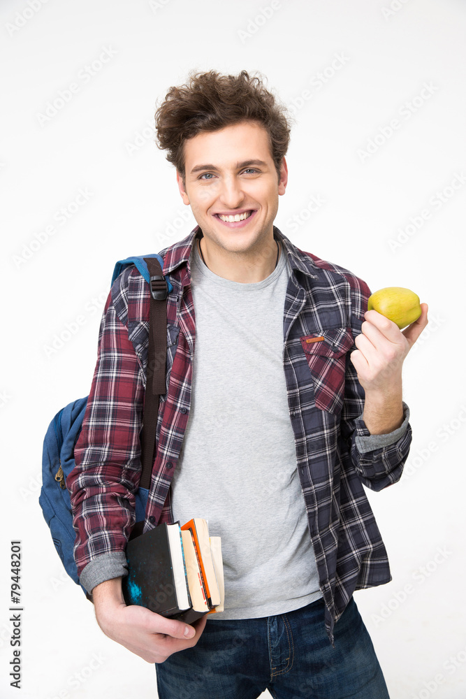 Young happy male student standing with books and apple Young happy male student standing with books and apple