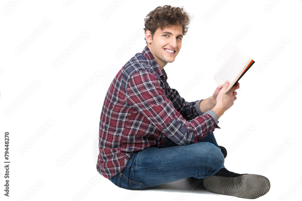 Side view portrait of a happy man sitting on the floor with book