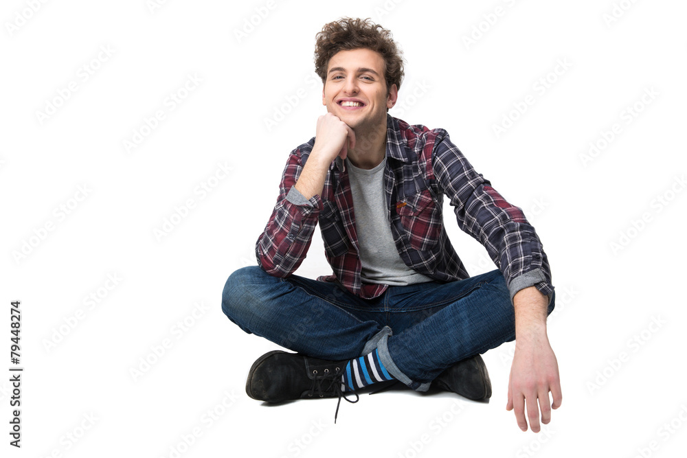 Smiling young man sitting on the floor over white background Smiling young man sitting on the floor over white background