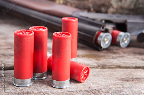 Photography 12 gauge shotgun shells with shotgun on wood surface