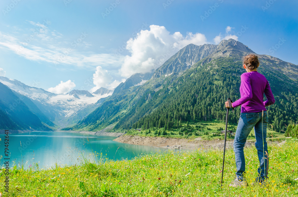 A young mountaineer stands beside an azure mountain lake
