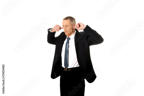 Businessman plugging his ears