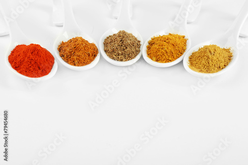 Different kinds of spices in ceramics spoons isolated on white