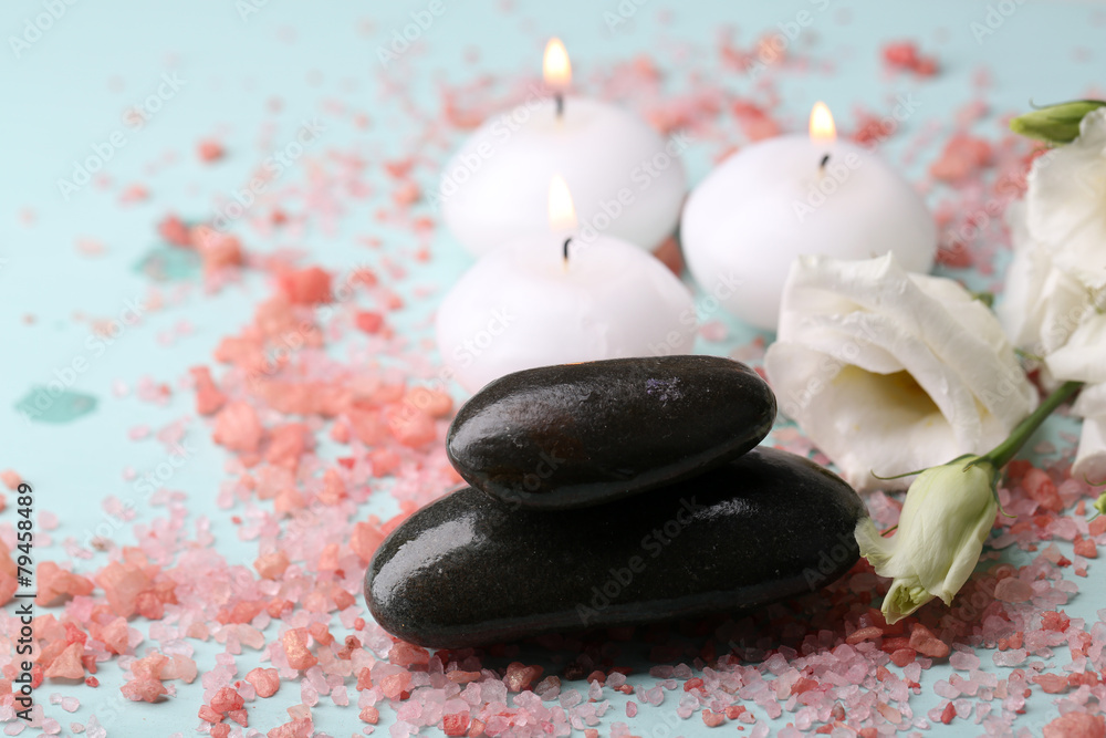 Obraz premium Spa stones with candles and flowers on blue background close-up
