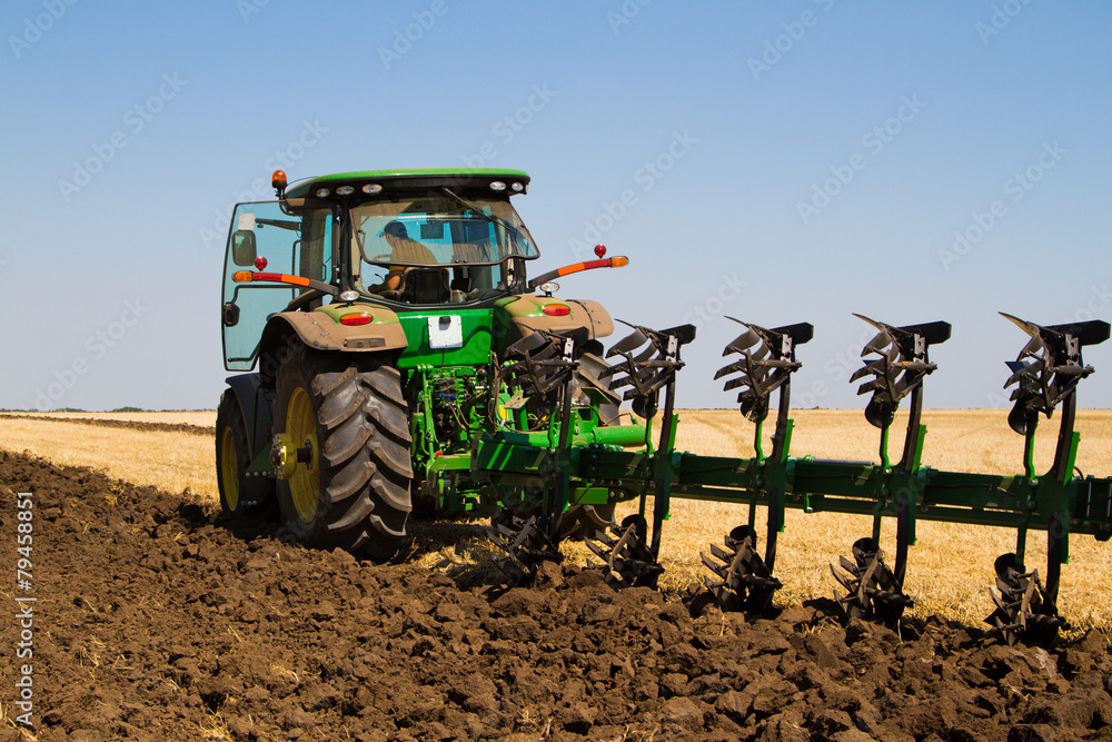 Fototapeta premium Agricultural tractor plowing a field