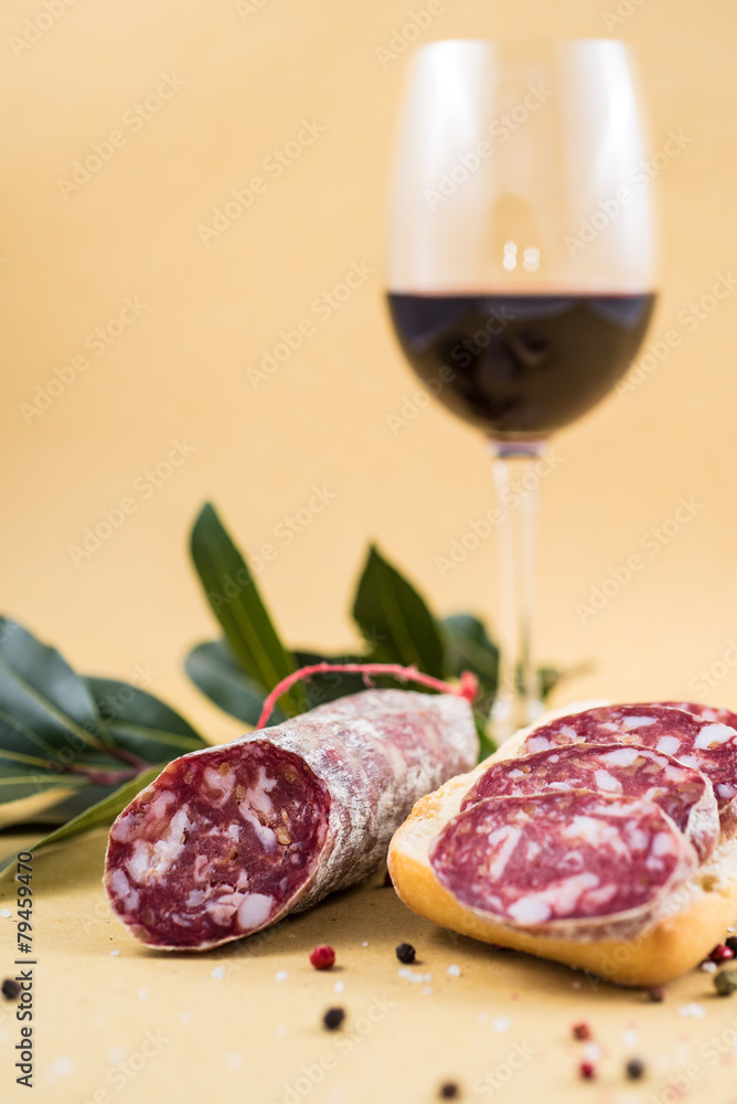 slices of italian salami on bread and some spices and wine