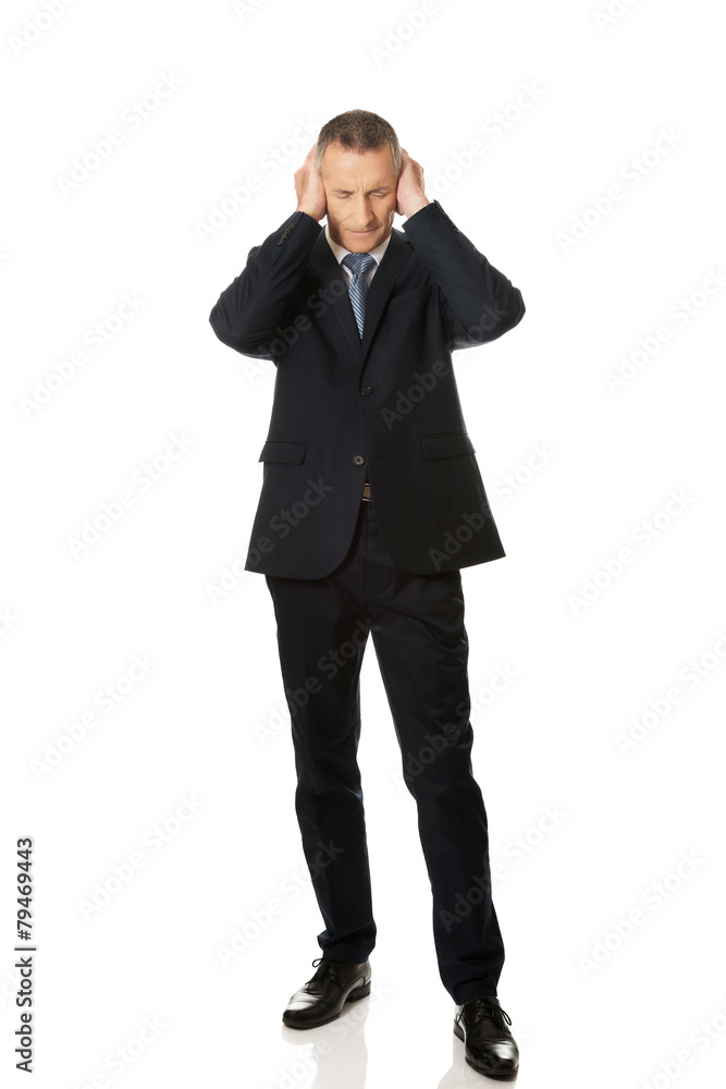 Tired businessman covering ears with hands Tired businessman covering ears with hands