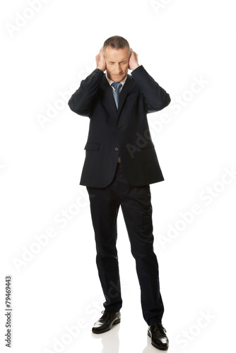 Tired businessman covering ears with hands