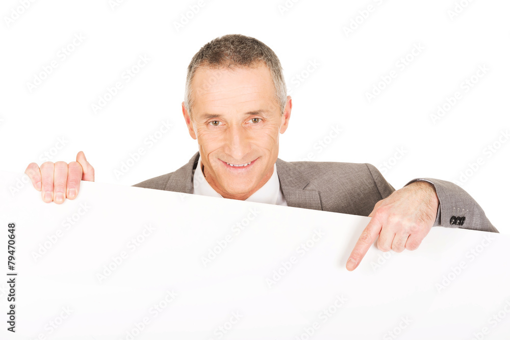 Smiling businessman pointing on empty banner Smiling businessman pointing on empty banner