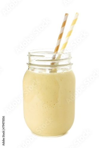 Banana smoothie in a mason jar with straws over white