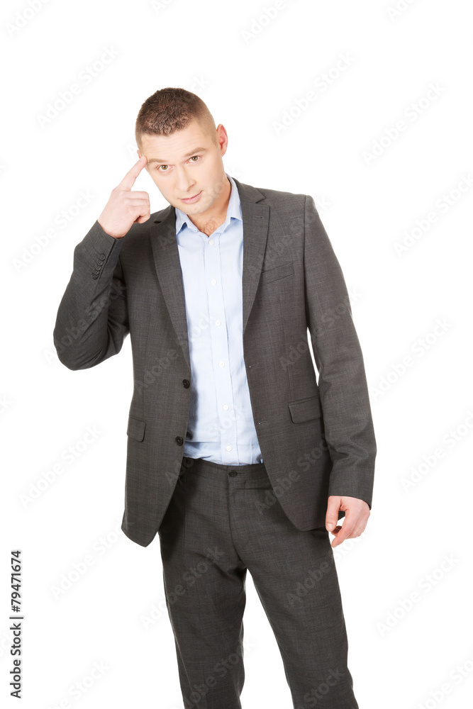 Businessman gesturing with finger against temple Businessman gesturing with finger against temple