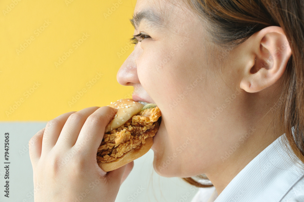 Asian woman age 28 years old in uniform eating chicken burger, j Asian woman age 28 years old in uniform eating chicken burger, j