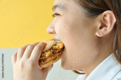 Asian woman age 28 years old in uniform eating chicken burger  j