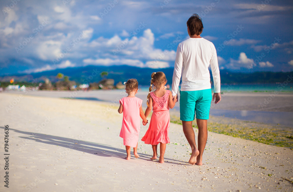 Happy family of two girls and young dad on white beach during
