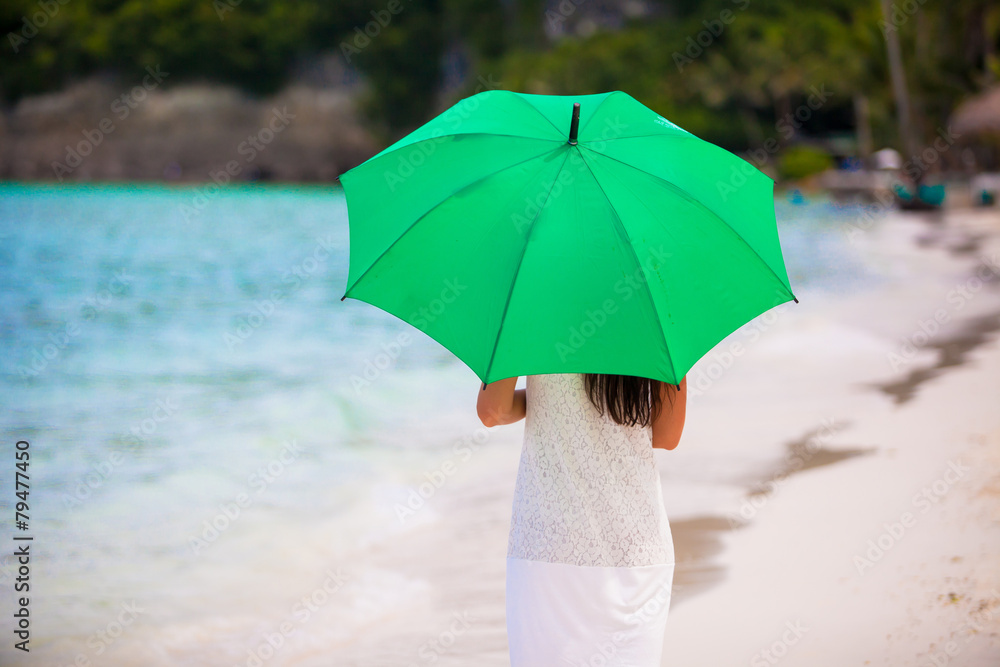 Young girl with umbrella on white beach
