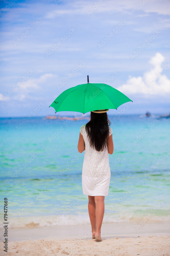 Young girl with umbrella on white beach