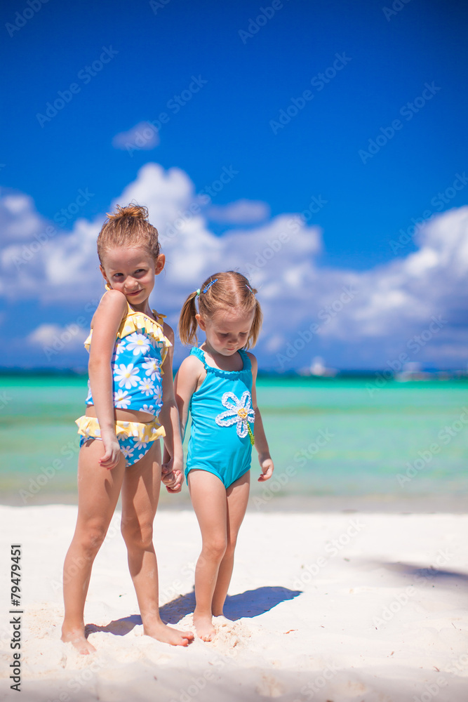 Adorable little girls have fun on white beach during vacation