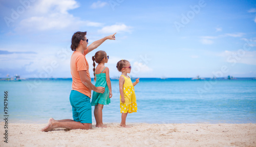 Little girls and young dad on white beach during summer vacation