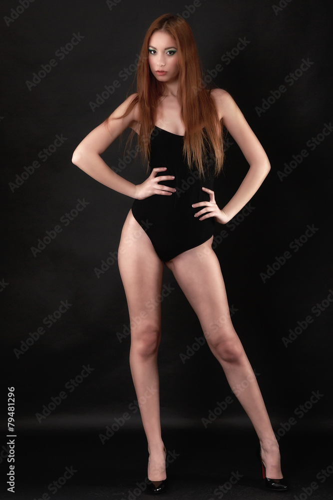 Beautiful woman in a black bodysuit posing on a black background Beautiful woman in a black bodysuit posing on a black background
