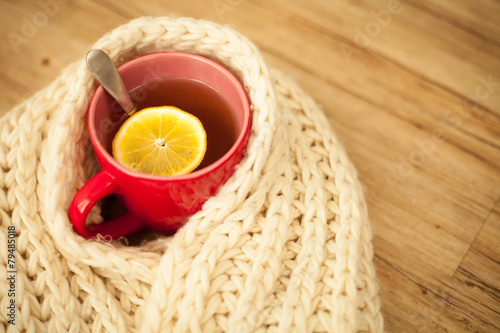 Sickness concept  Cup of hot tea and lemon wrapped with a scarf