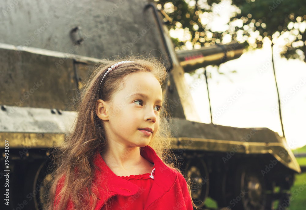 Toned  portrait of little girl near military tank at sunset