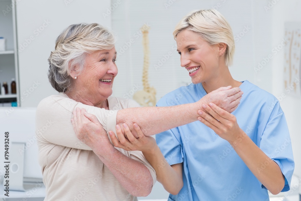 Obraz premium Happy nurse assisting patient in raising arm
