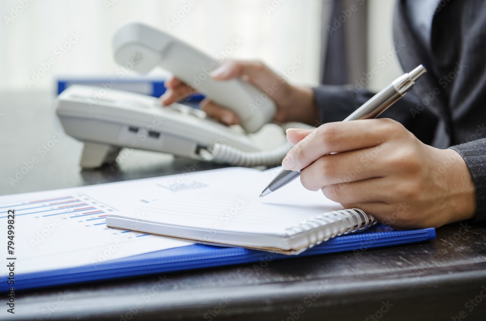 Businesswoman dialing and writing on note book Businesswoman dialing and writing on note book