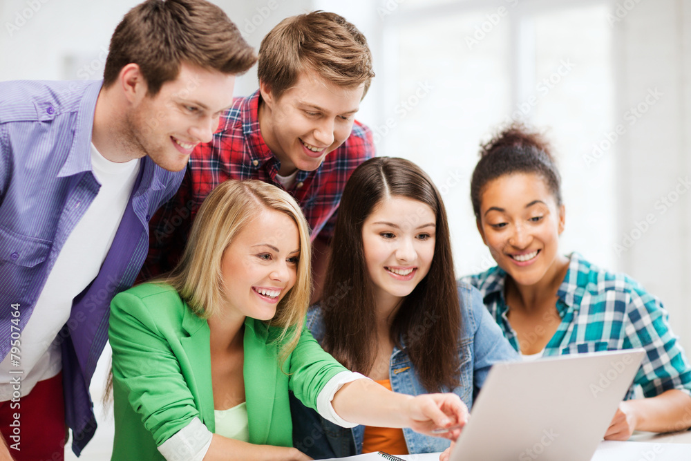 smiling students looking at laptop at school smiling students looking at laptop at school