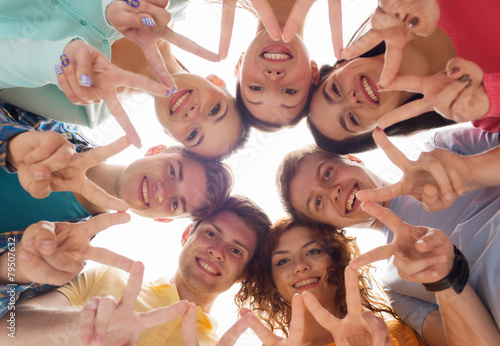 group of smiling teenagers showing victory sign