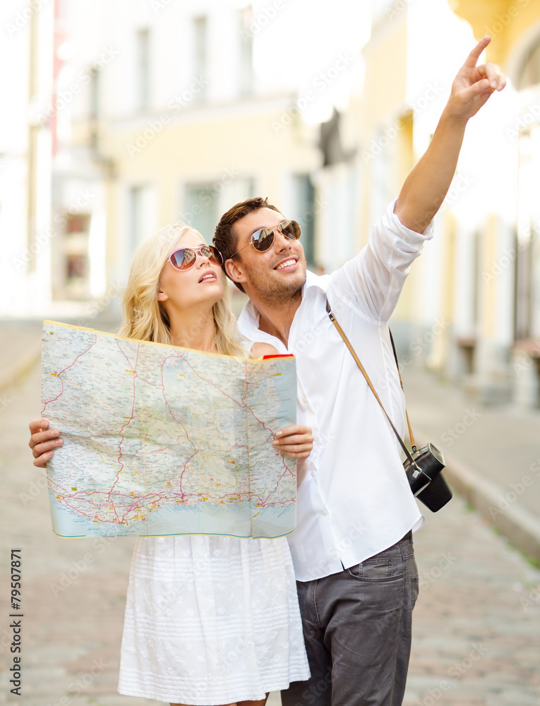 smiling couple in sunglasses with map in the city