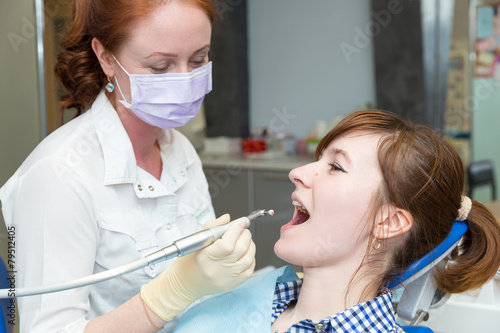 Dentist with drill and girl in chair