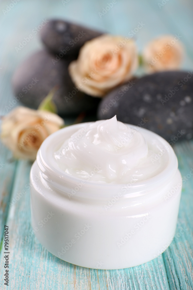 Cosmetic cream with flowers and spa stones on wooden background Cosmetic cream with flowers and spa stones on wooden background