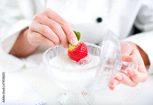 Hand holding strawberry covered in sugar