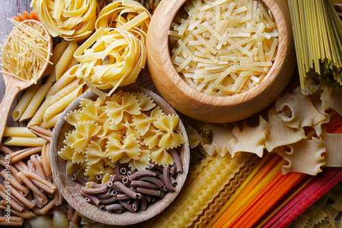 Different types of pasta with wooden bowls, macro view
