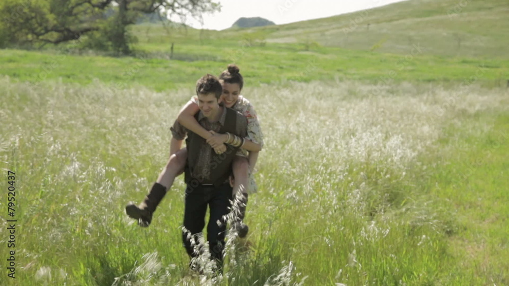 Man giving his girlfriend a piggyback ride in nature Man giving his girlfriend a piggyback ride in nature