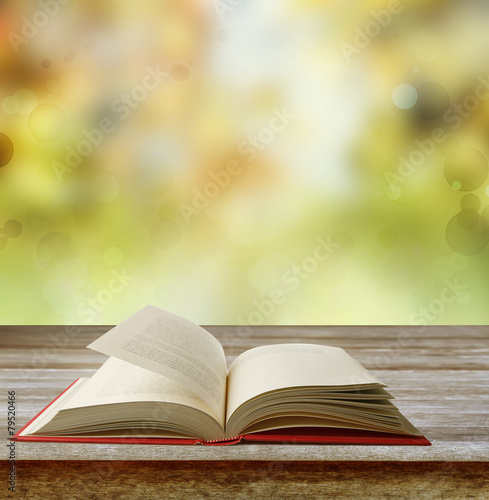Open book on table and blurred spring background