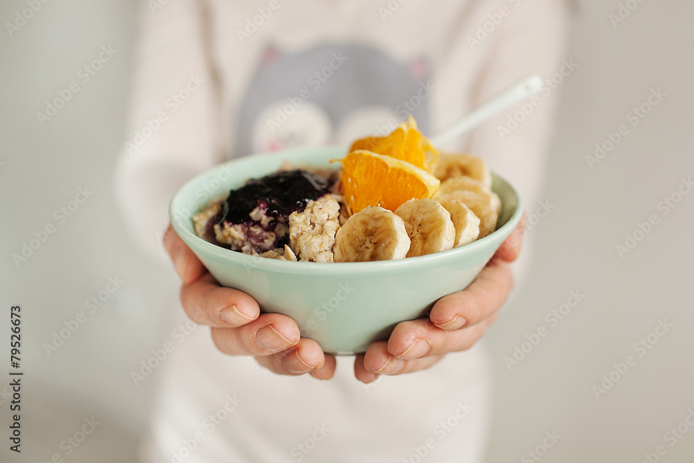 Woman holds plate with porridge and fruits Woman holds plate with porridge and fruits