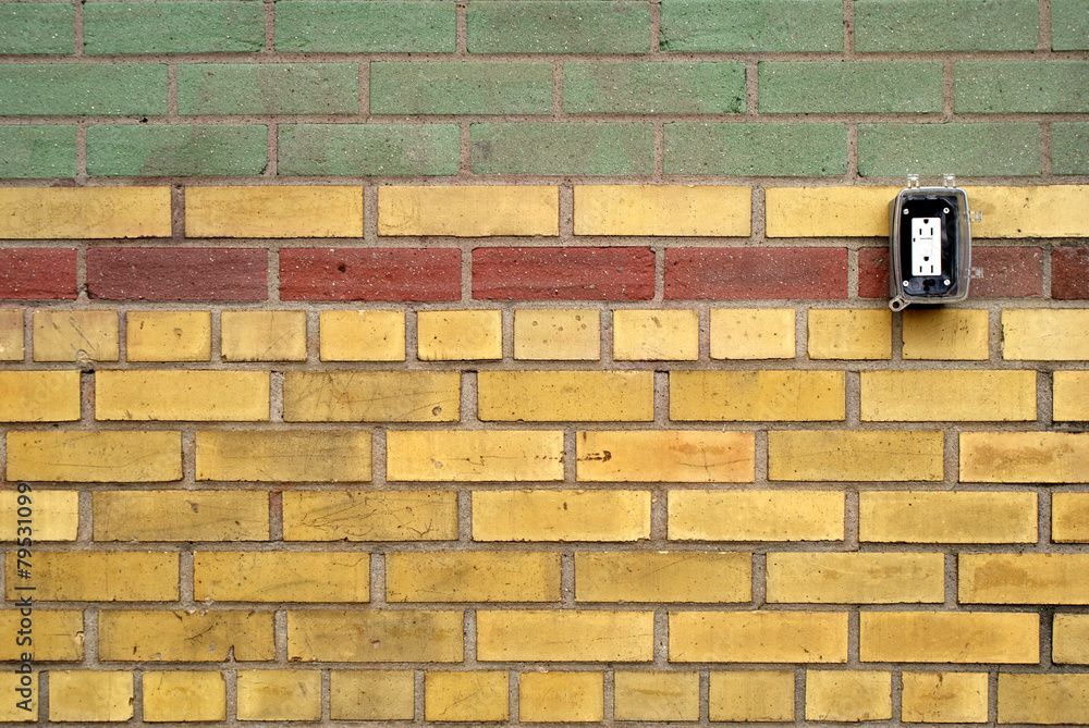 Wall of coloured bricks in pattern with electrical outlet Wall of coloured bricks in pattern with electrical outlet