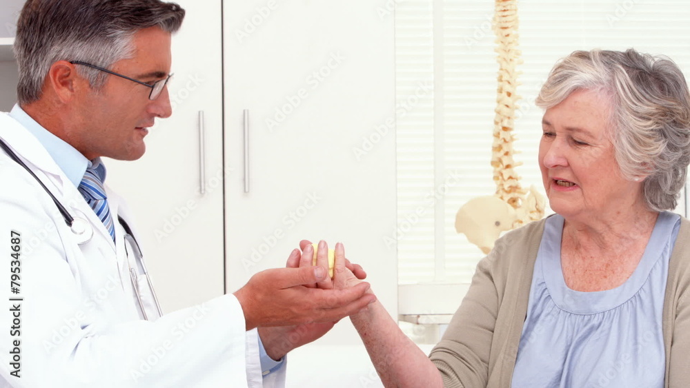 Doctor showing patient how to exercise injured hand Doctor showing patient how to exercise injured hand