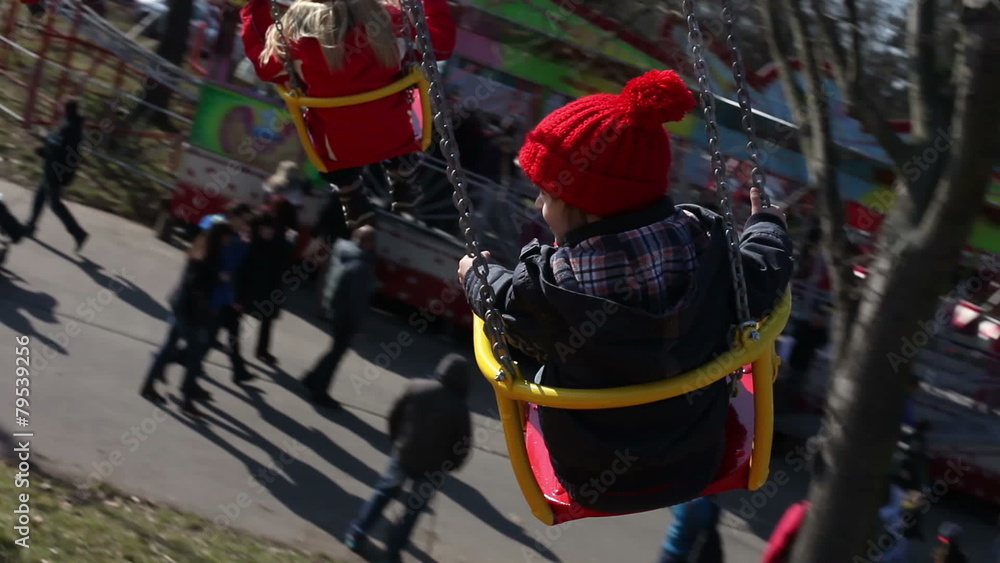 Adorable boy, going on a merry-go-round chain swing attraction Adorable boy, going on a merry-go-round chain swing attraction