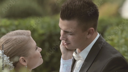 Cute bride stroking the face of groom standing among the leaves