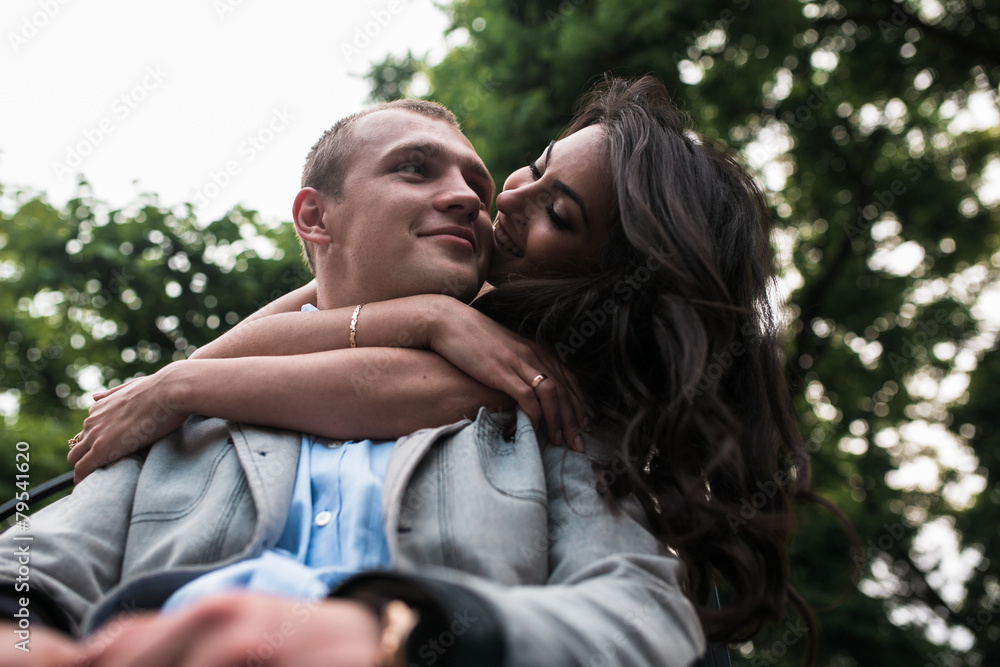 Fototapeta premium Young European couple cuddling on a park bench