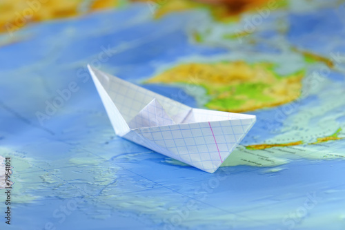 Paper boat on a background map of the world